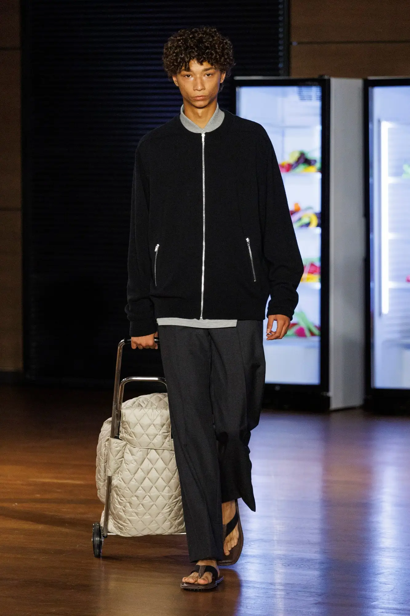 Look 24. Black jacket, a cream quilted trolley.