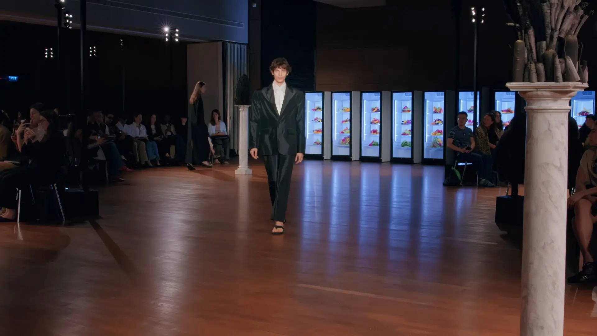 Look 1 walks in front of the fridges.