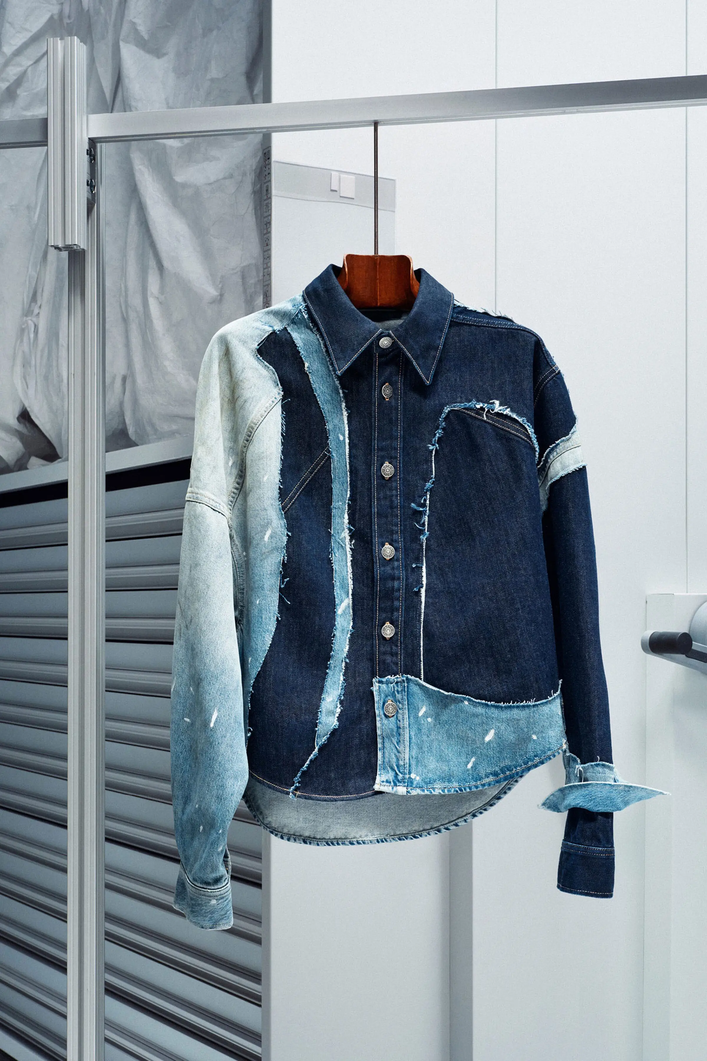 The Patchwork Denim Shirt on a hanger at the V&A East Storehouse.